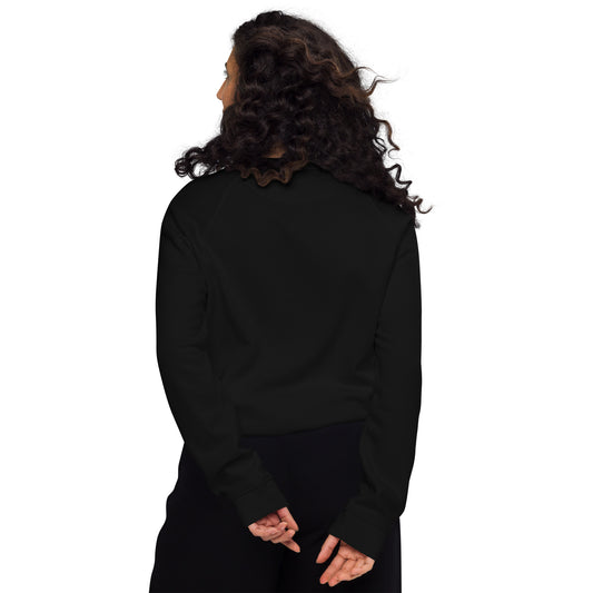 Black organic raglan sweatshirt with long sleeves and ribbed cuffs, shown from the back on a model with curly hair.