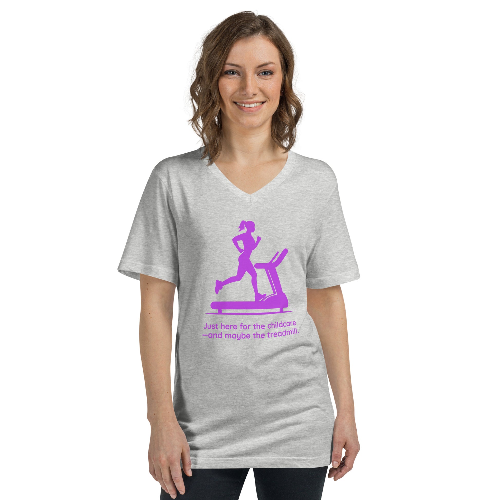 Light gray V-neck tee with purple graphic of a woman on a treadmill and text "Just here for the childcare — and maybe the.