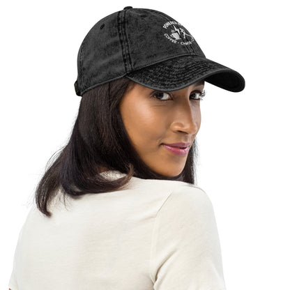 Black vintage cotton twill cap with white "Powered by Coffee, Chaos & Cardio" embroidered text and curved brim.