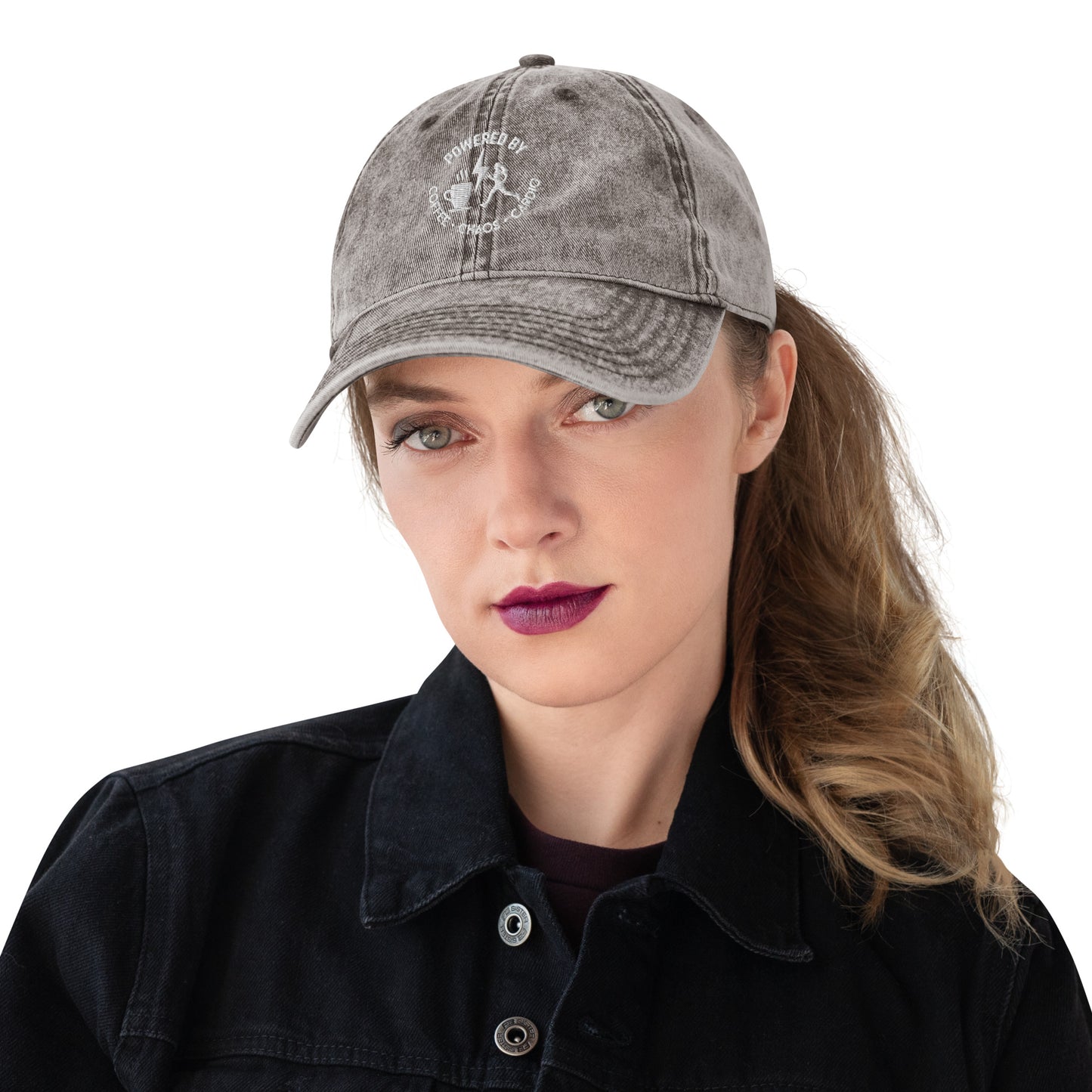Charcoal grey vintage cotton twill cap with white embroidered "Powered by Coffee, Chaos & Cardio" text on front worn by woman.