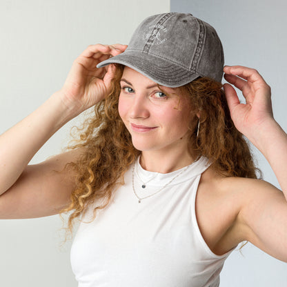 Charcoal grey vintage cotton twill cap with embroidered "Powered by Coffee" script worn by woman with curly hair.