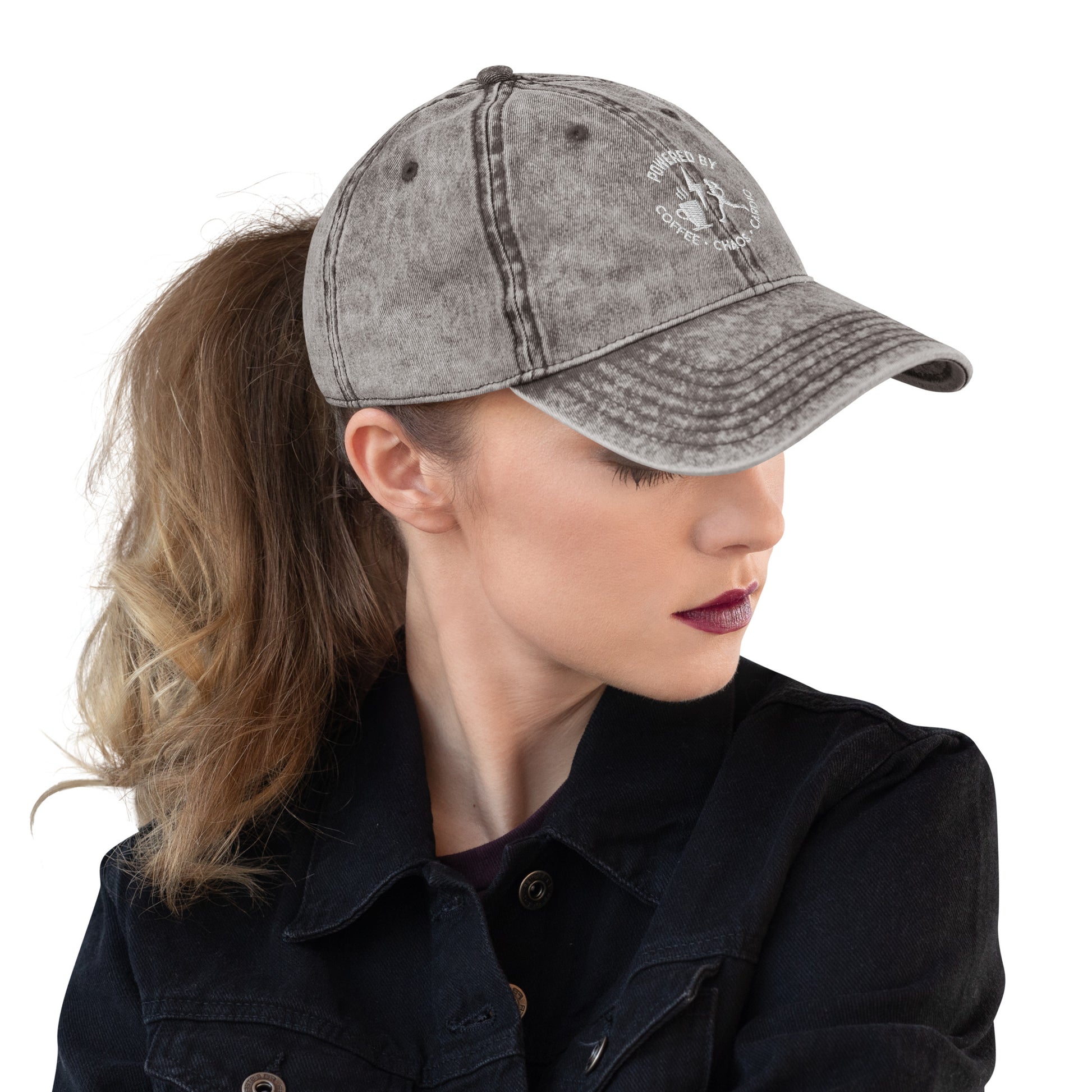 Charcoal grey vintage cotton twill cap with embroidered "Powered by Coffee, Chaos & Cardio" text, worn with ponytail and.