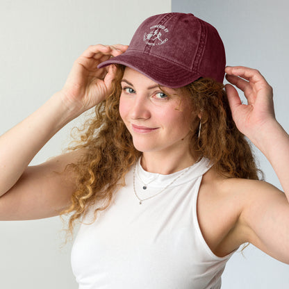 Maroon vintage cotton twill cap with white embroidered "Powered by Coffee, Chaos & Cardio" text worn by woman.