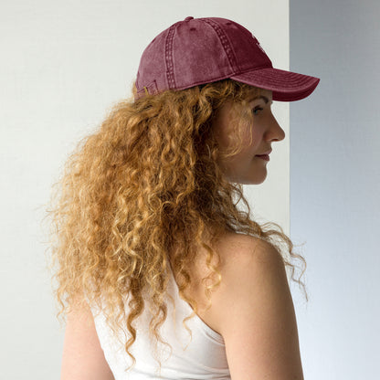 Maroon vintage cotton twill cap with curved brim, worn on side view by woman with curly hair.