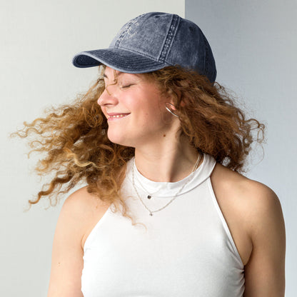 Charcoal grey vintage cotton twill cap with curved brim and embroidered slogan on front worn by woman.